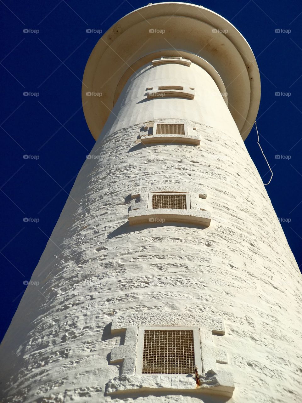 Ground up perspective, old stone lighthouse against vivid blue sky, Point Lowly, South Australia 