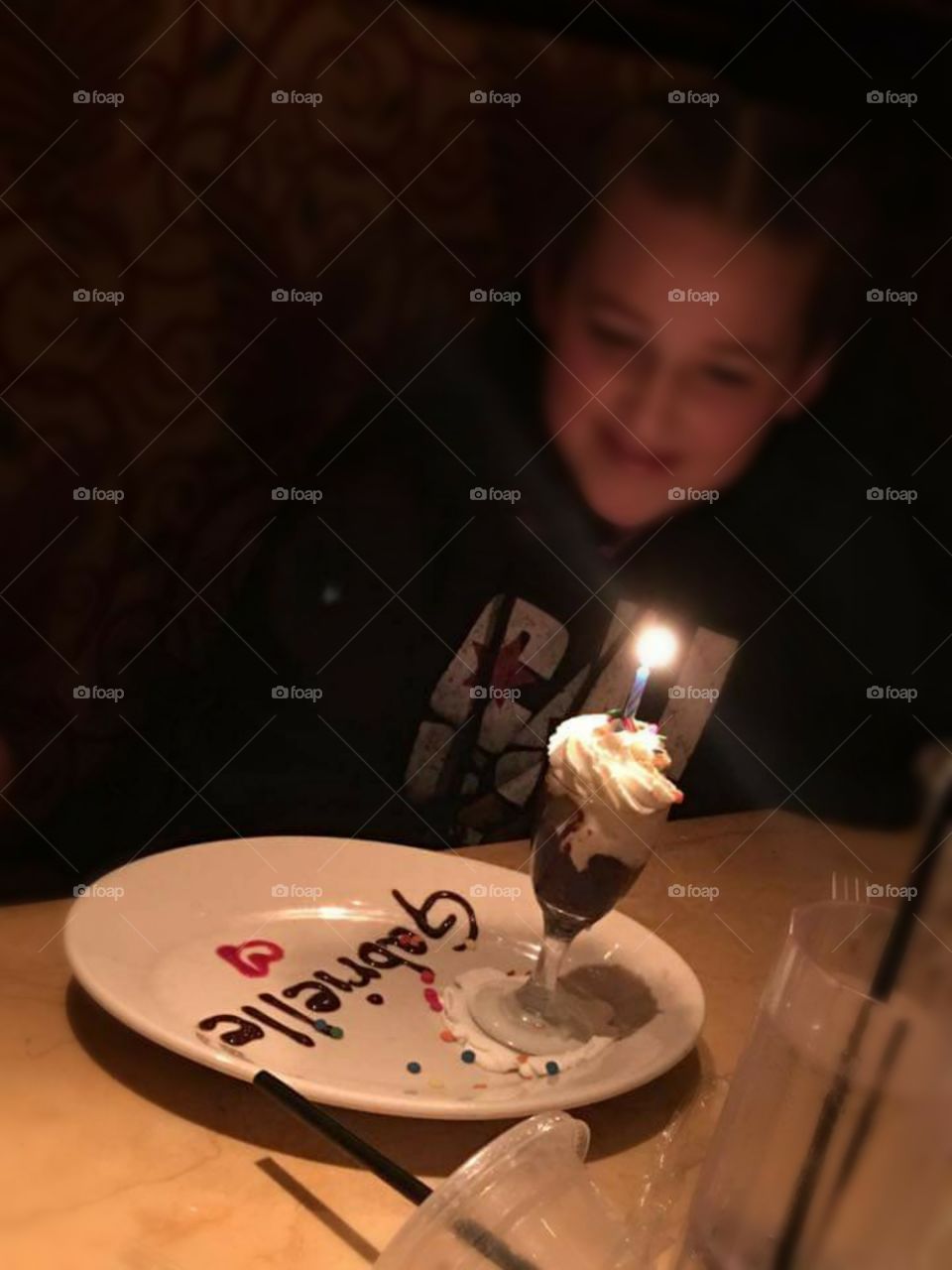 Girl looks at her candle-lit birthday treat with excitement and anticipation.