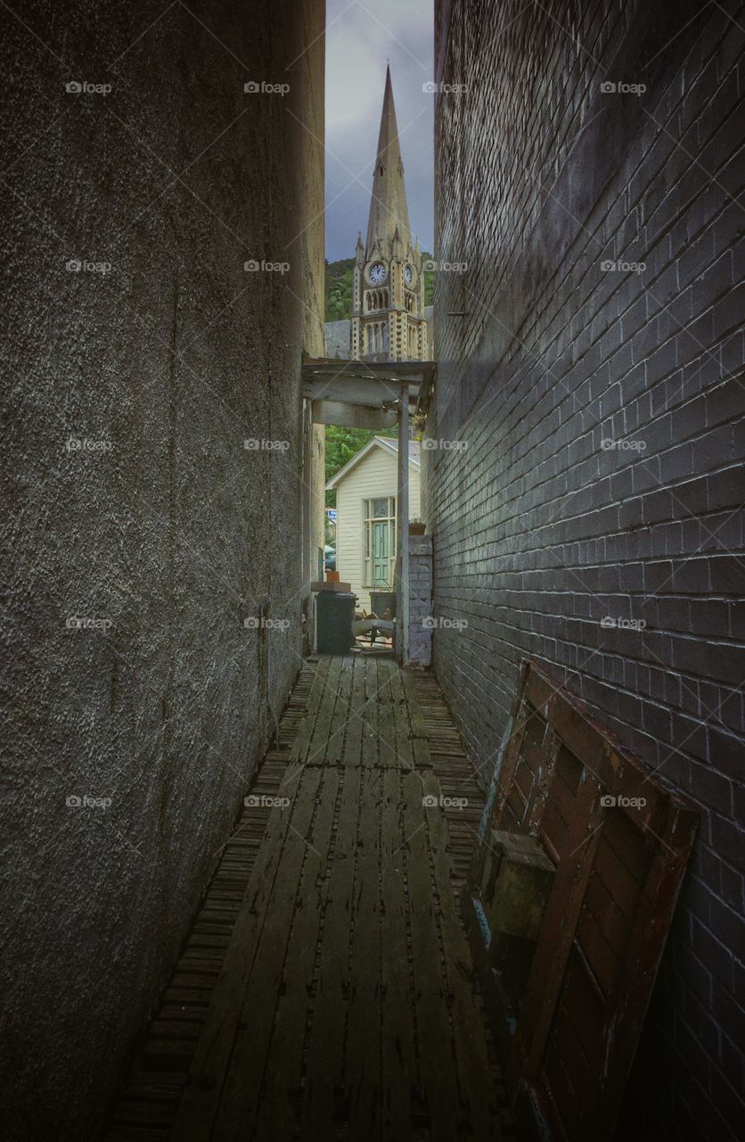 Church steeple seen through a narrow alley