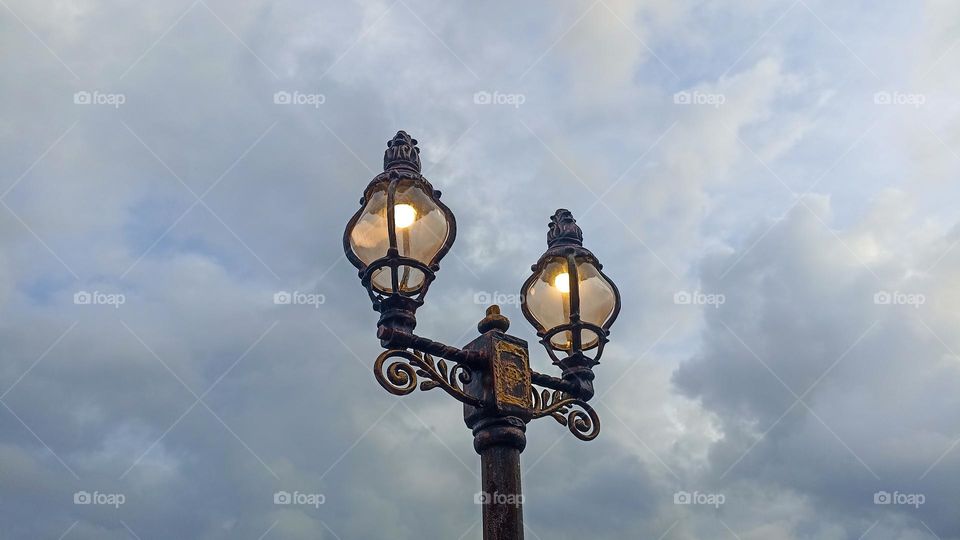 Low angle view of illuminated street light against cloudy sky