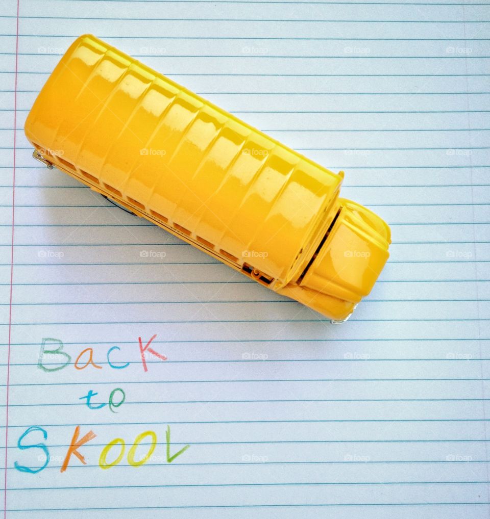 Back To School Concept With Toy Yellow School Bus And Child's Writing "Back to Skool" written in crayon