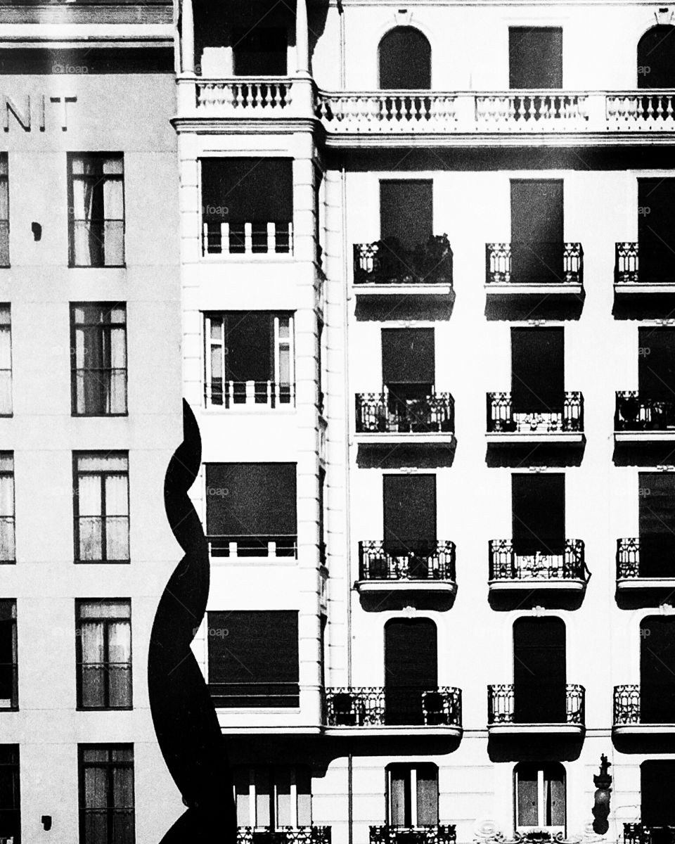 Night rises in-between.. An urban photo of a statue and some windows.
