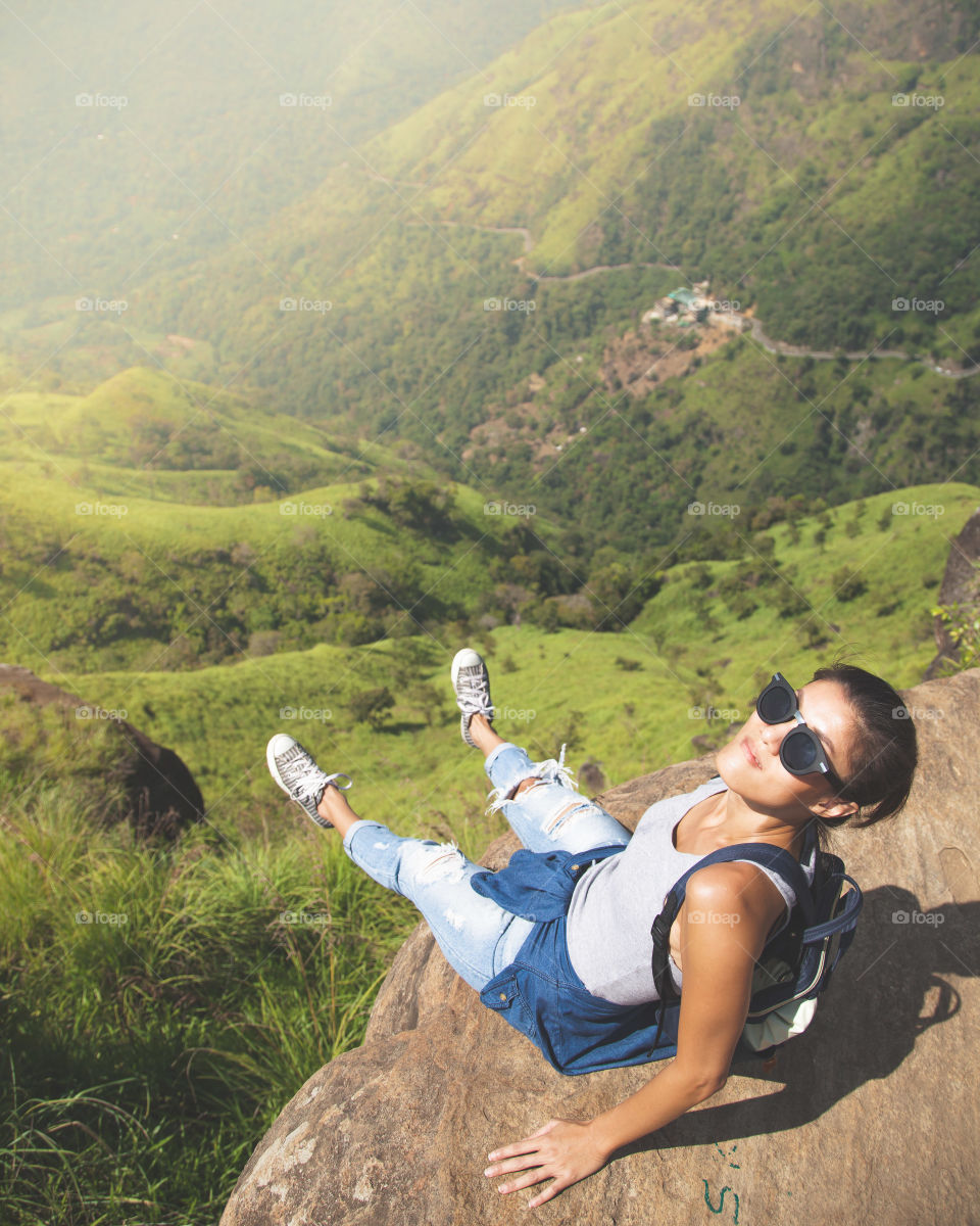 Young woman sitting on rock above the valley