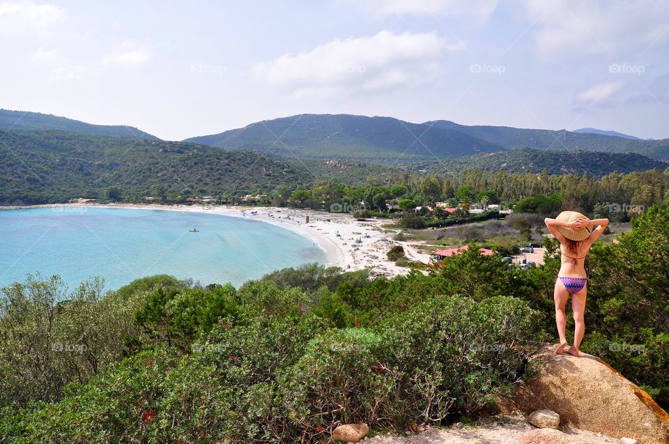 beautiful beach view on sardinia island in italy with young woman in the sumner hat