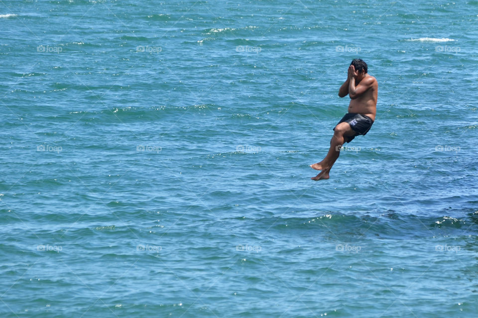 Man jumps into ocean ,covering his face