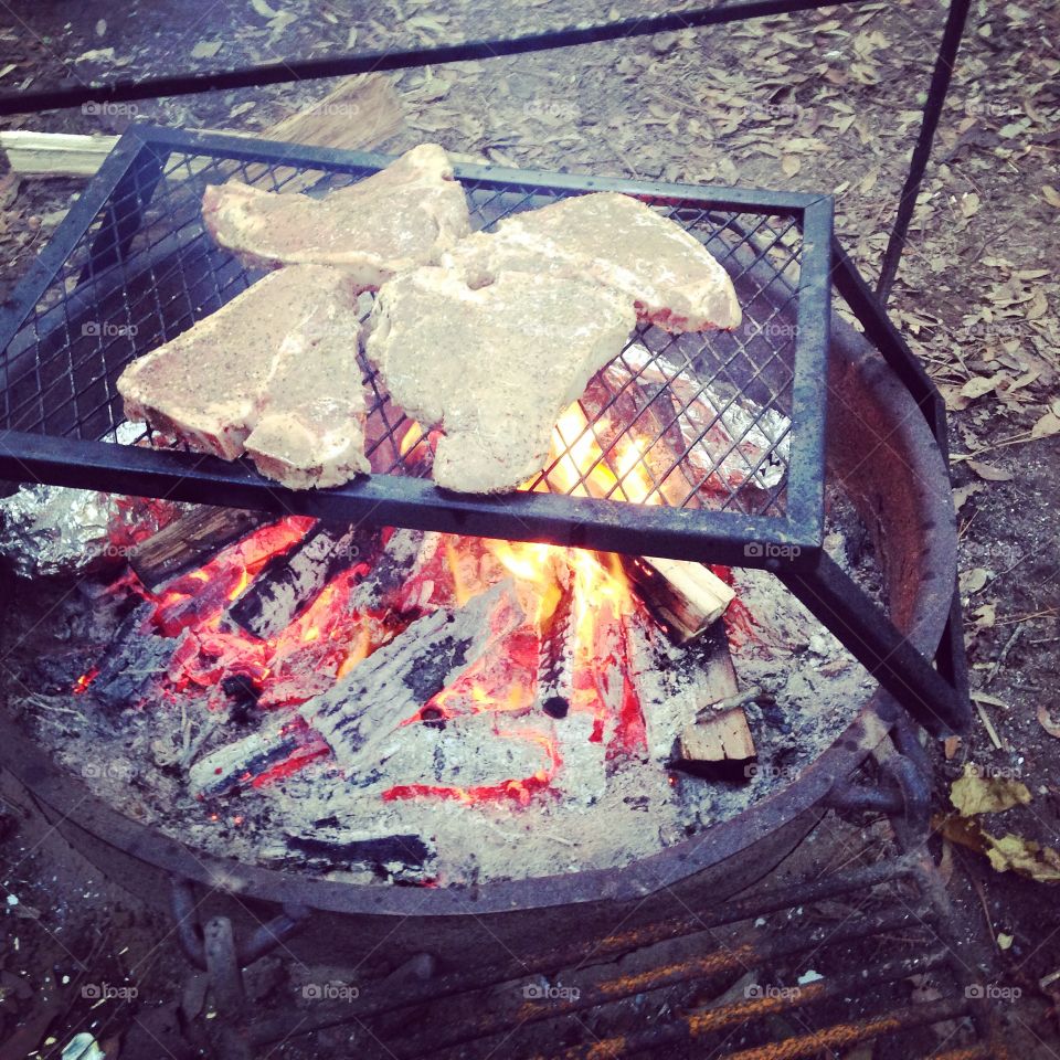 Steaks over a fire.