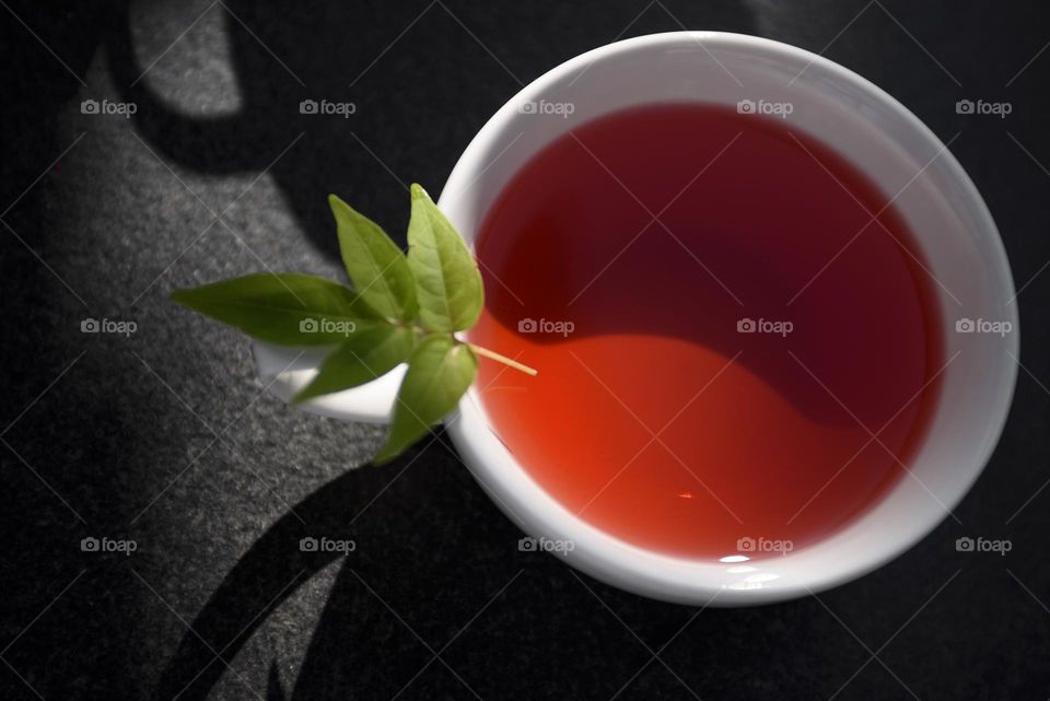 White cup with pomegranate tea on a black table.