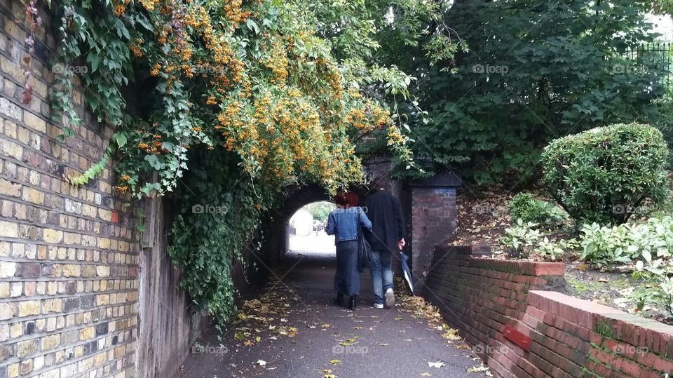 couple walking in fall street. a couple walking in a street under a brigde in autumn