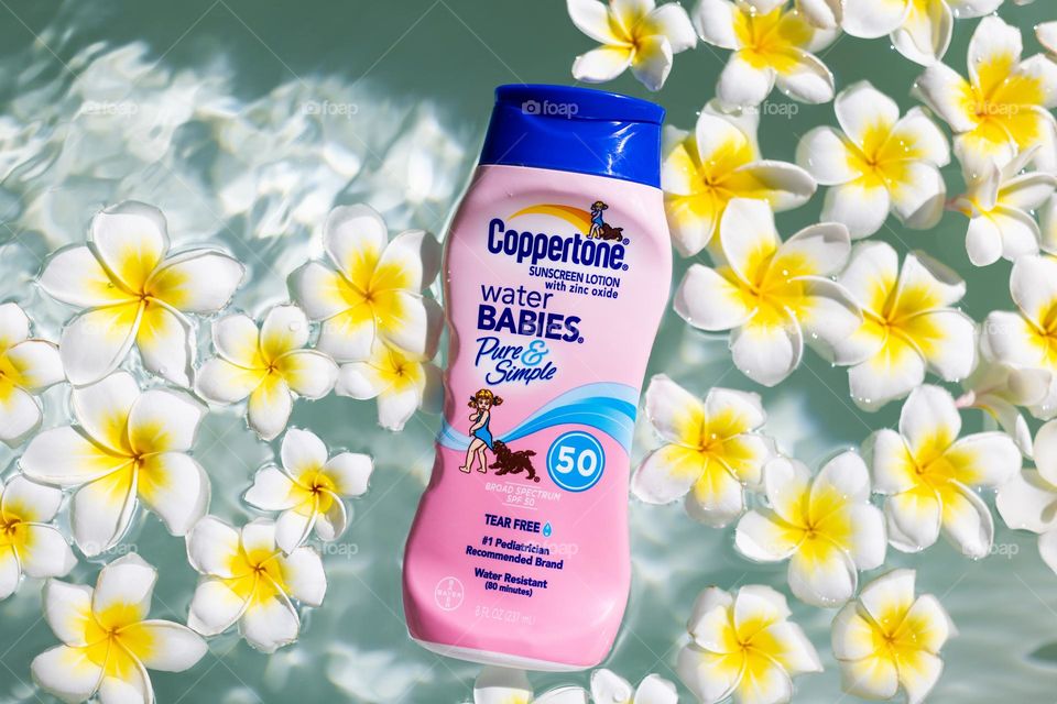 Spf sunscreen cream in bath with plumeria flowers