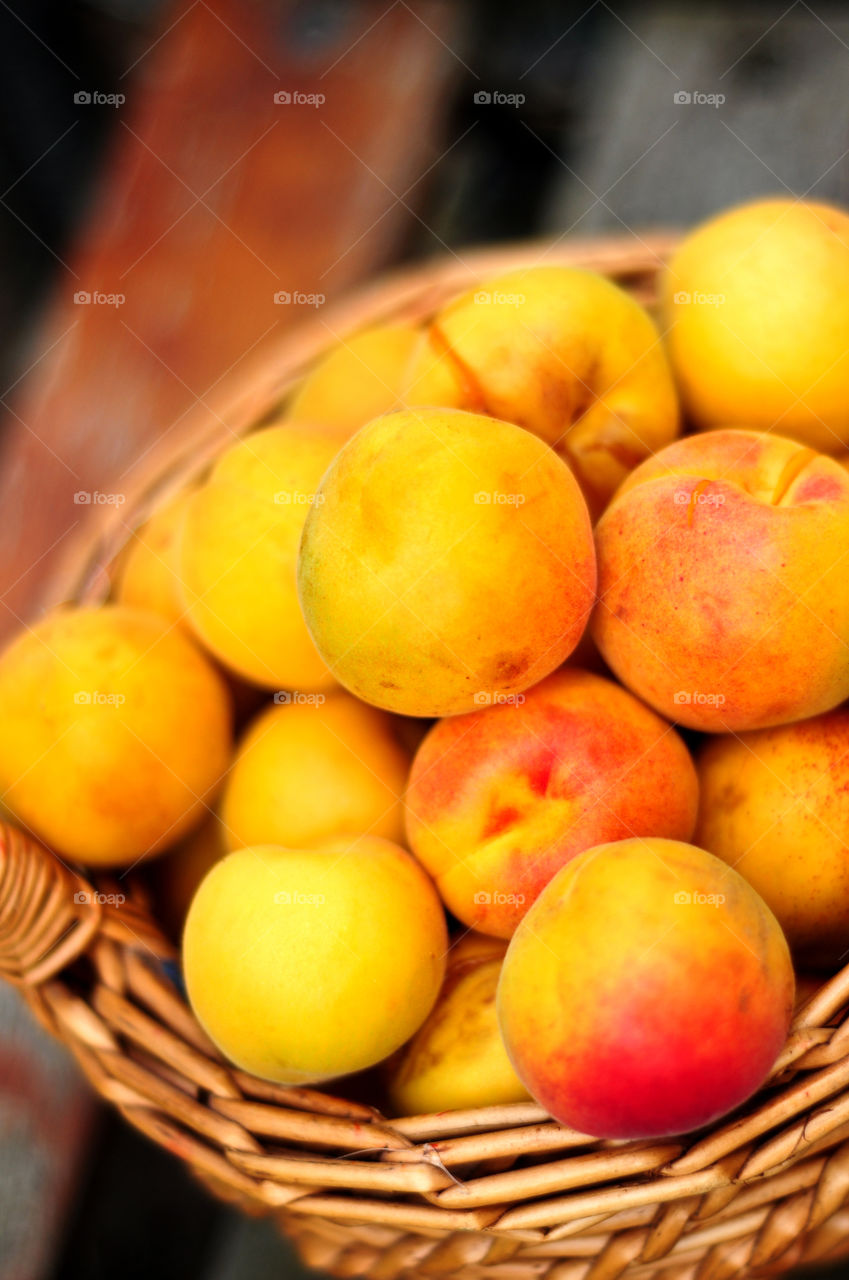 Fresh apricots summer fruits in basket on wood background