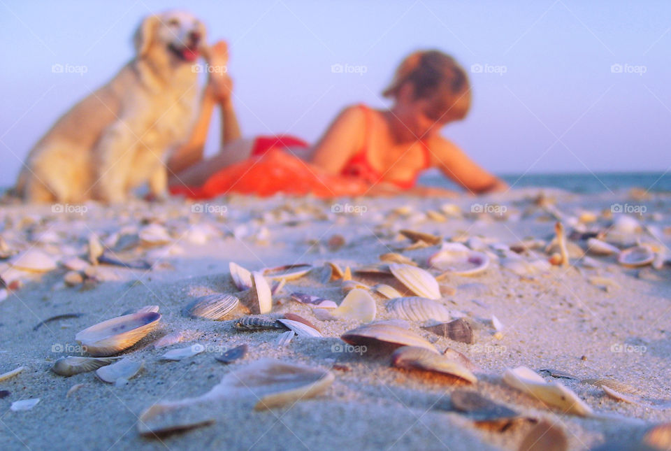 Girl with a dog lies on the beach