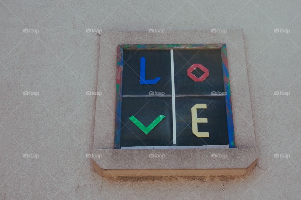 The word LOVE in colored letters on a window screen