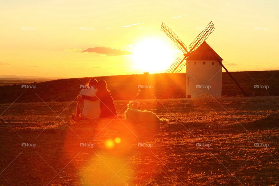 Couple sitting on field during sunset