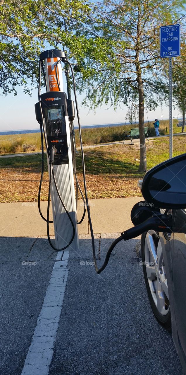 Electric car charging at a station parking lot at a park.