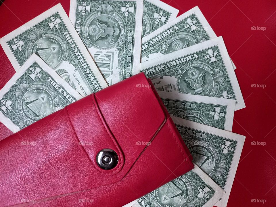 spread out money and a red wallet on a red background.