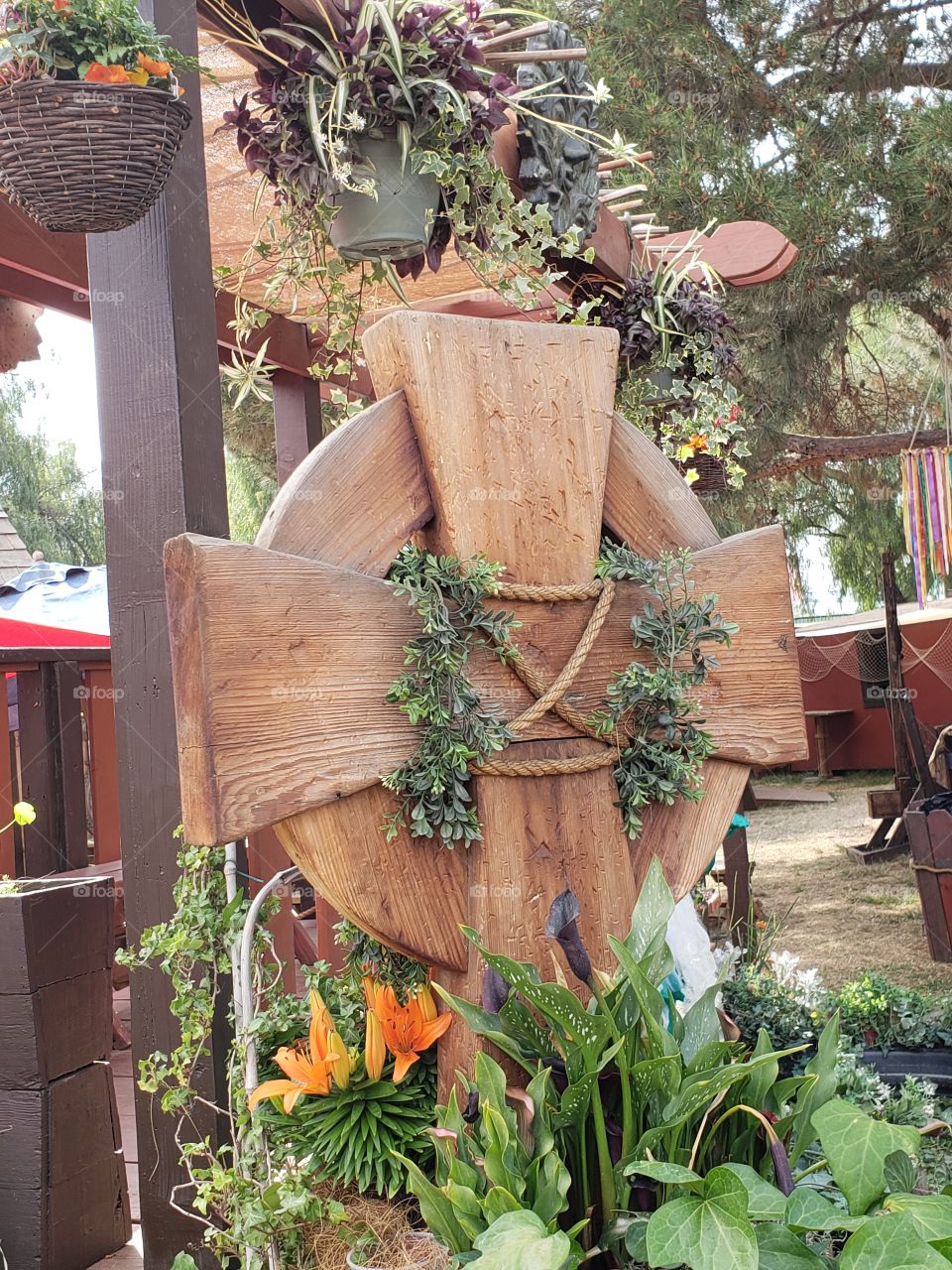 A wooden Celtic cross surrounded by colorful and gorgeous flora, a decoration at the Renessaince Fair.
