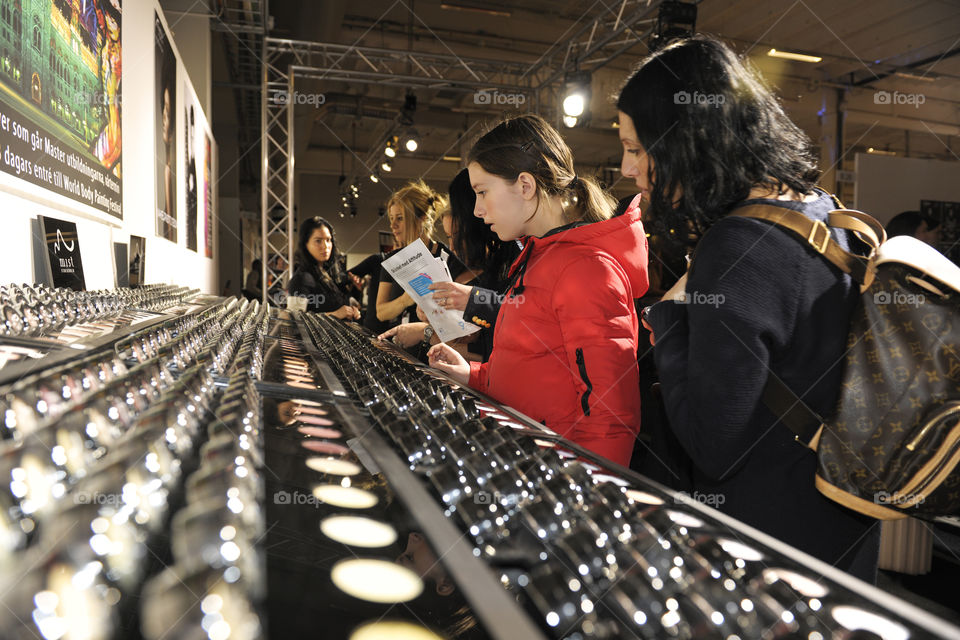 Young women shopping makeup at a fashion fair.