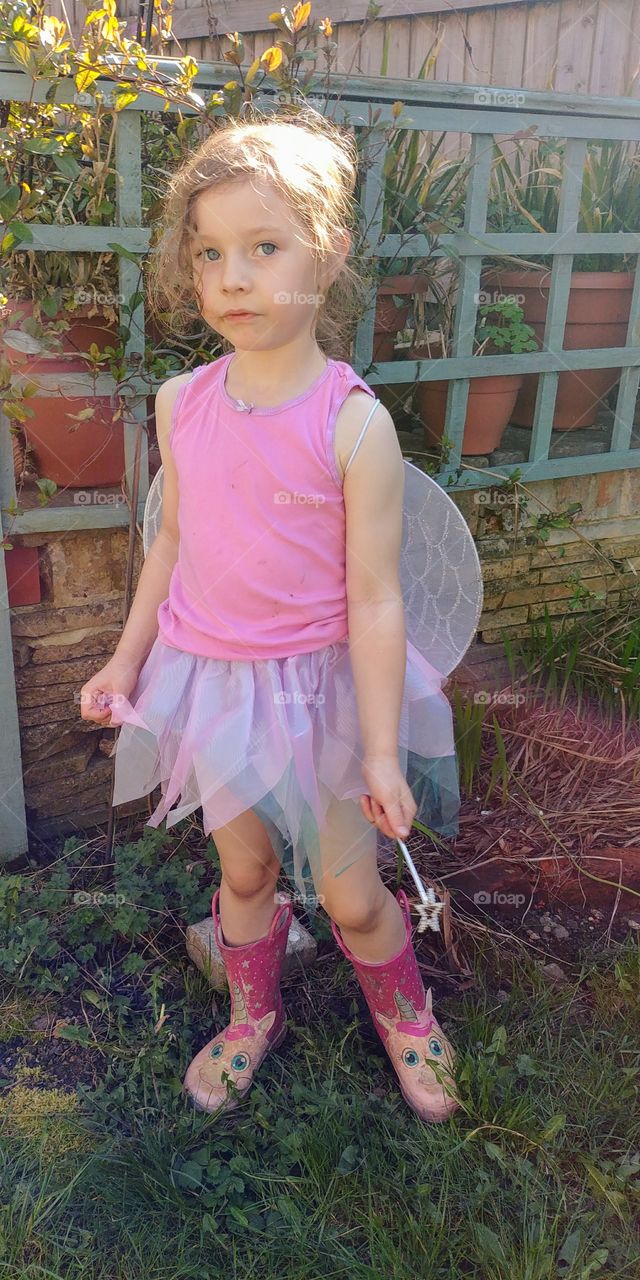 little girl in wellies and pink fairy outfit holding wand