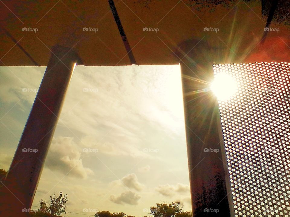 The sun shines from behind a building in a park in the city of Jakarta