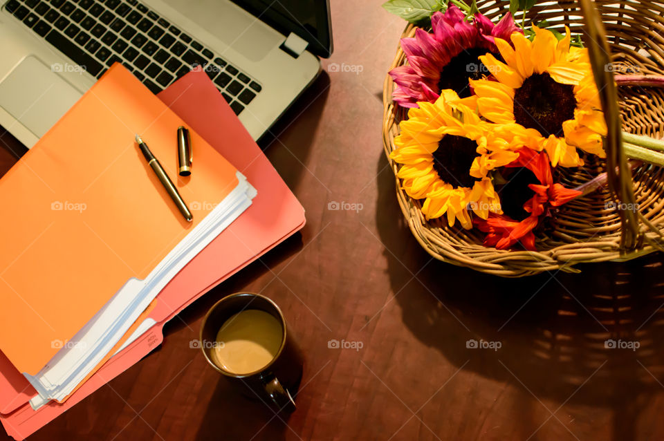 Bright Sunflowers  on desk with laptop, files with paper, fountain pen and cup of coffee elevated view conceptual work life balance tranquil business scene 