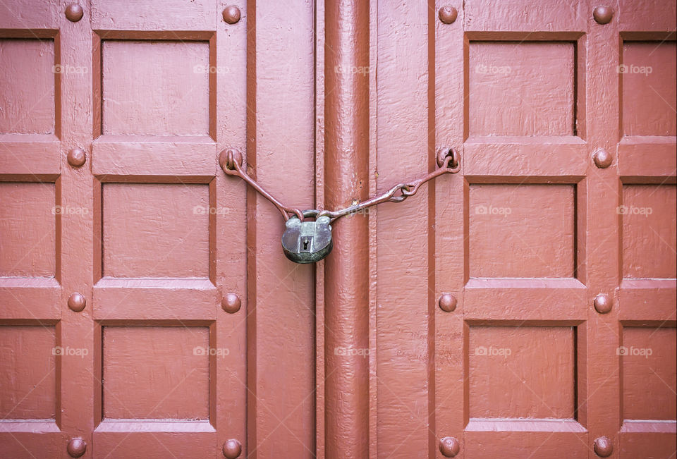 Old padlock on a red wooden door