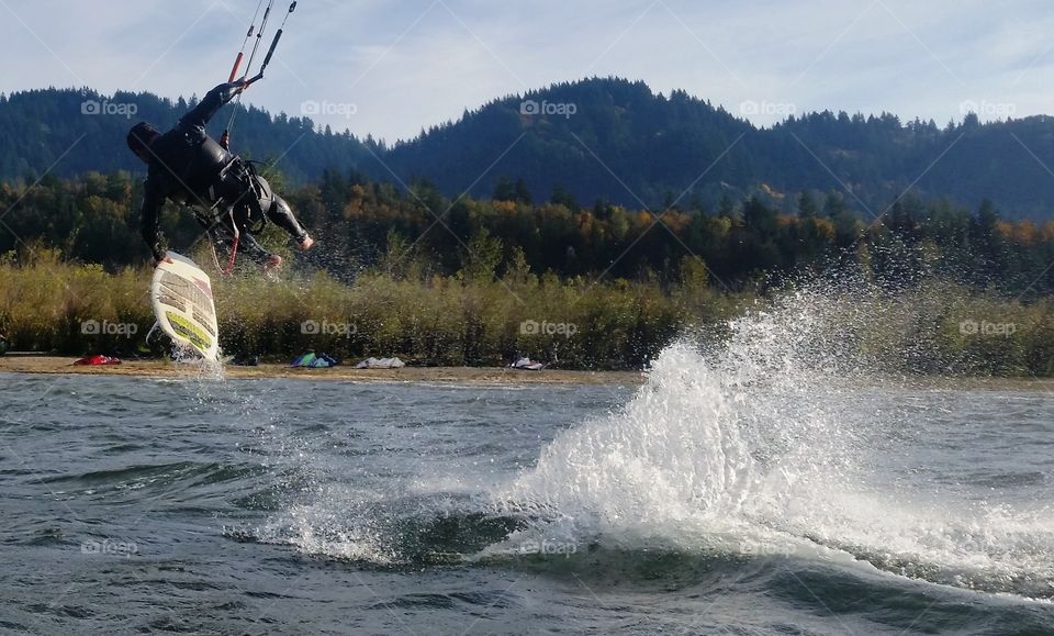 Man paragliding holding surfboard from water
