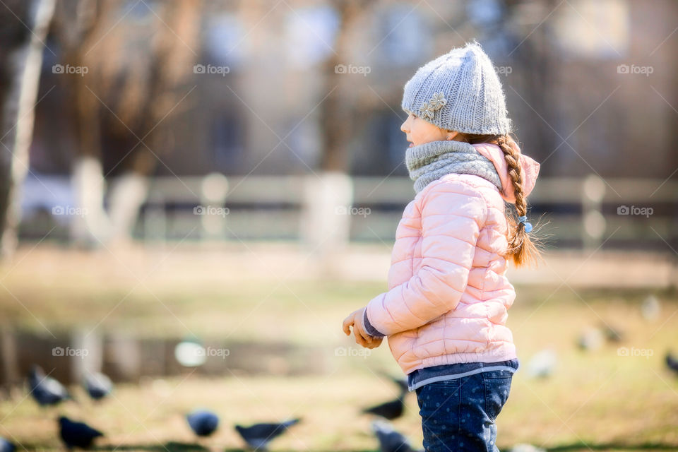 Little girl with pigeons in spring park. Little, girl, child, children, childhood, nature, park, outdoor, forest, spring, casual, portrait, pigeons, pond, water, birds, doves, walking, fun, playful, playing 