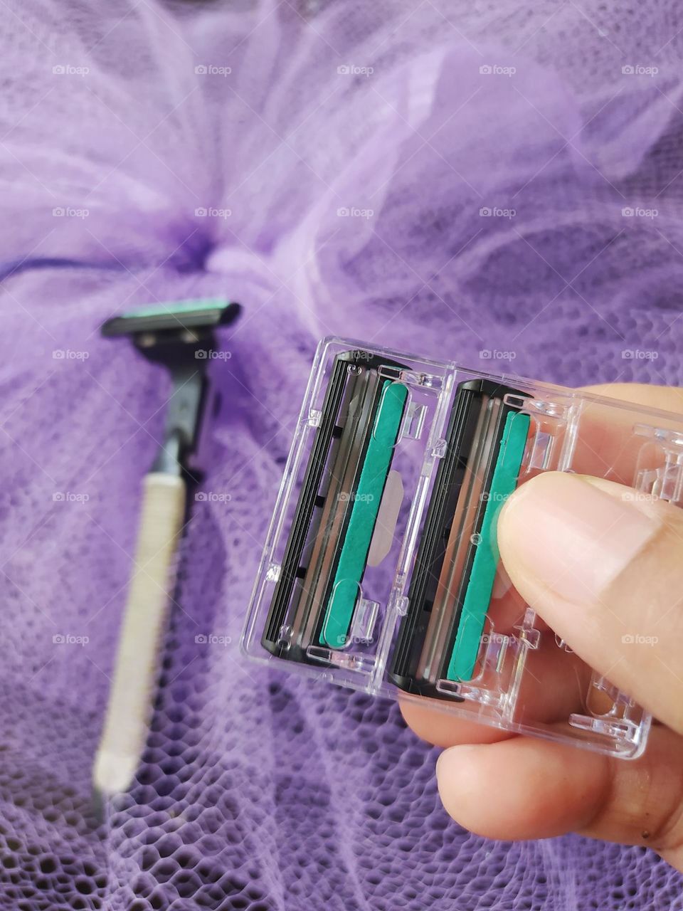 Gray razor, blade refill, purple netting background