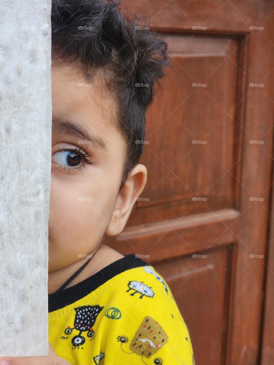 Boy peeking around wall stock photo