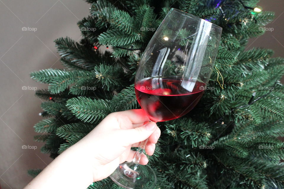 Glass of wine on Christmas tree background.
