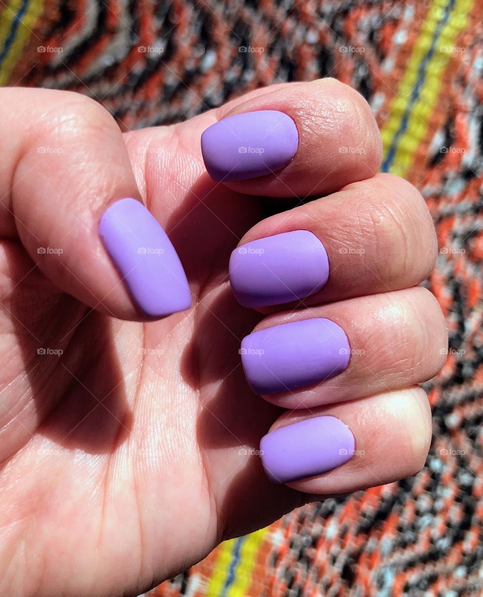 Pastel colors: lavender fresh trim matte nail polish on the lady’s finger nails 