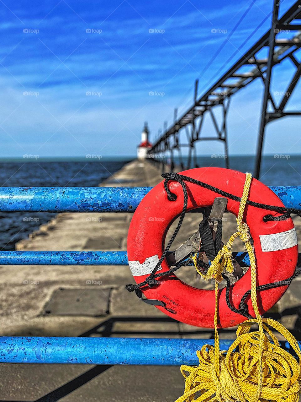 Michigan lighthouse in background of colorful scene, brightly colored lifesaver on Michigan pier, walking on the pier in Michigan, brightly colored sea life 