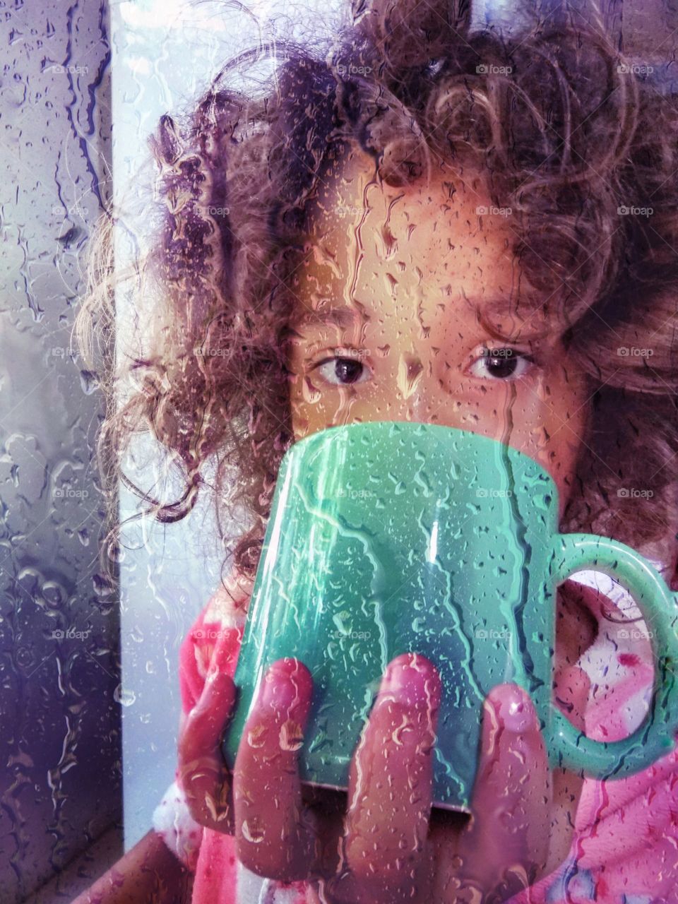 Girl drinking coffee from a mug on a rainy day.