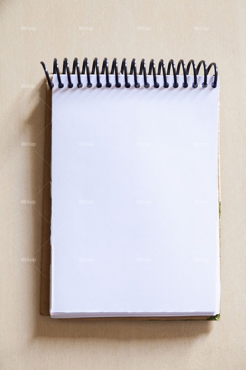 Blank notepad on the wooden table, with a red pen at the side, with sunlight hitting the side. Notepad for noting reminders. Annotation concept. Object concept. Copy space