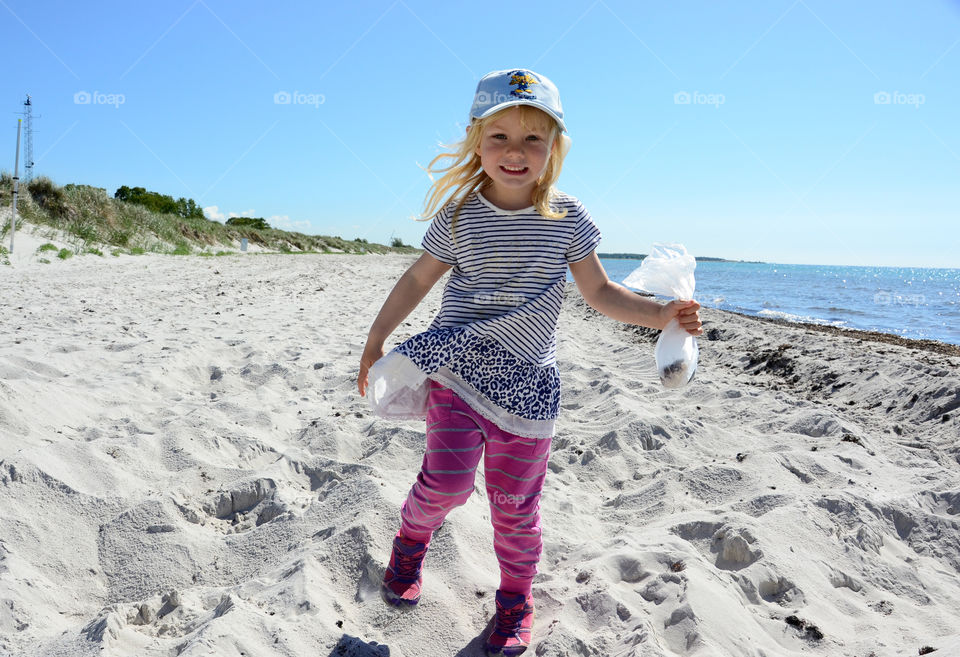 Young girl of five years old is searching for shells on the beach at Falsterbo.