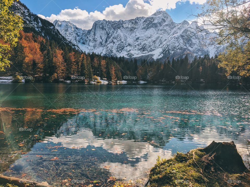 View of the autumn snow-capped mountain peaks against the backdrop of a transparent Italian lake.