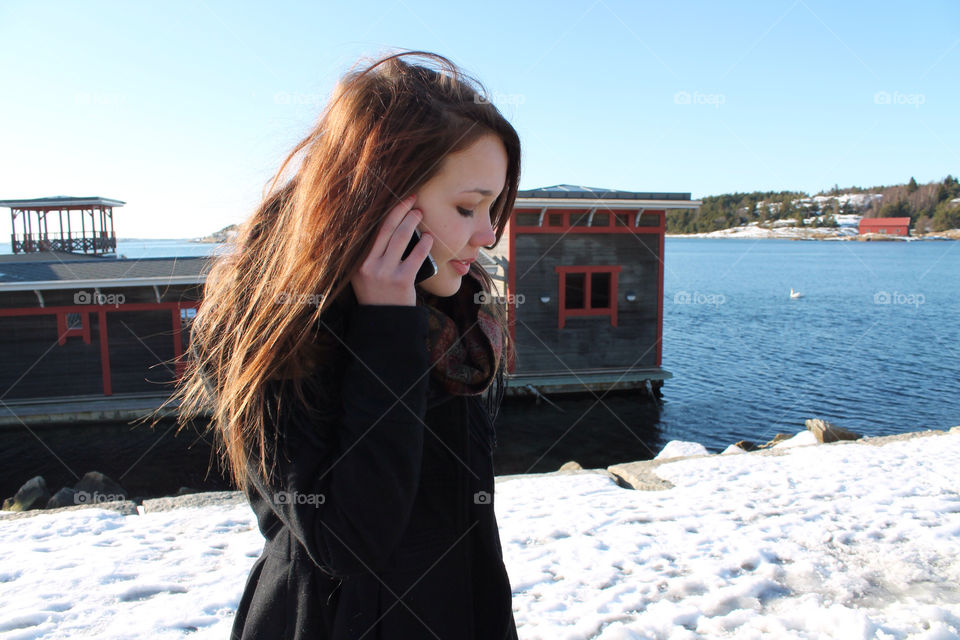 Girl talking in a cell phone. A girl walking outdoor in winter landscape 
and speaking in a cell phone