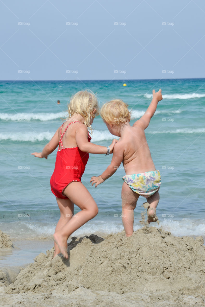 Young sisters playing at the beach in Majorca on their holiday.