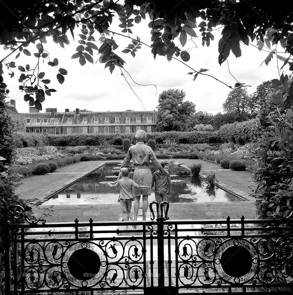 Black and white shot of the vintage looking Sunken garden of London's Kensington Palace with a view on the back of Princess Diana statue and the art deco gate