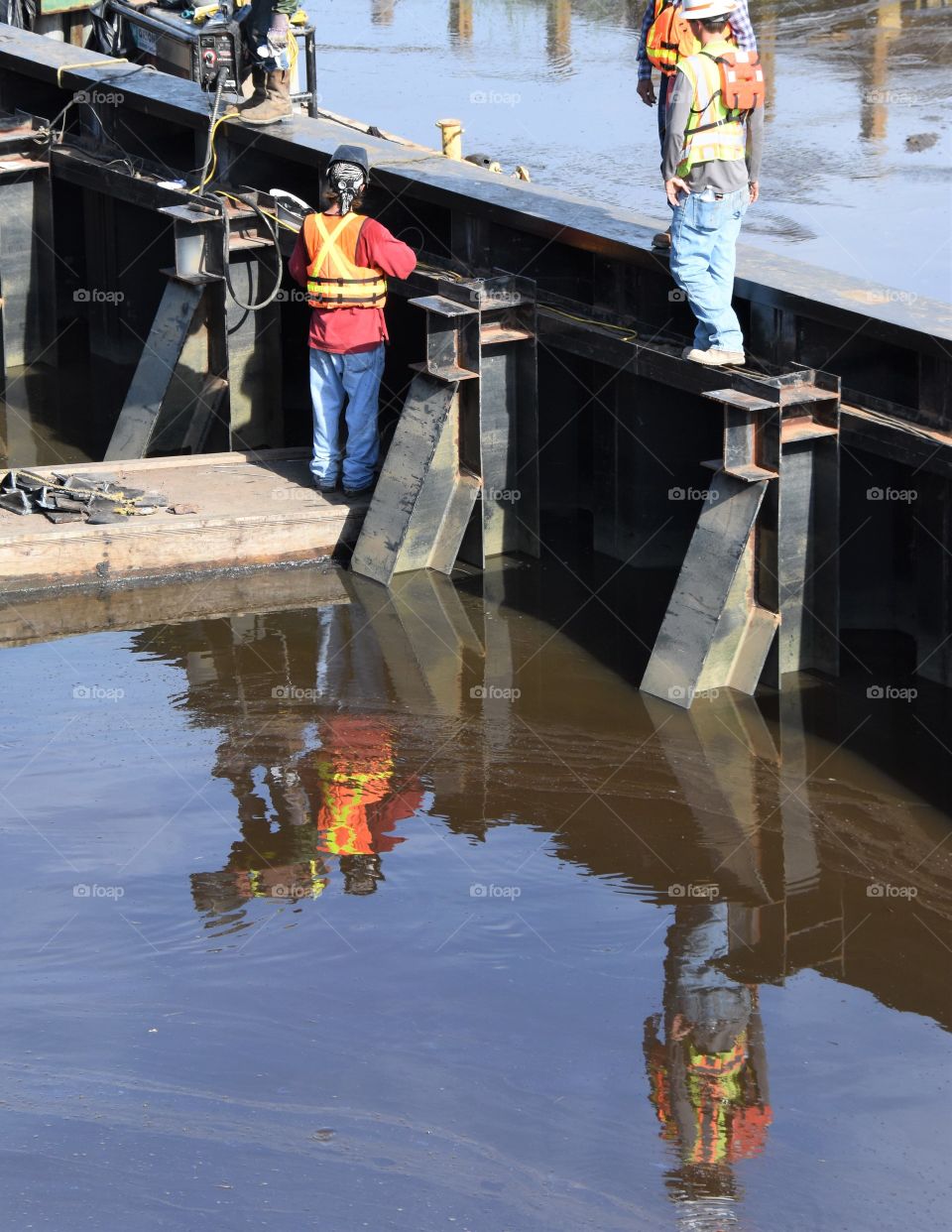 Construction workers with reflection in water