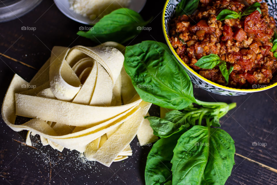 Homemade Pasta cooking food flat lay fresh pasta with basil leaves bowl of meat sauce and fresh Parmesan conceptual cooking and cozy home kitchen background 