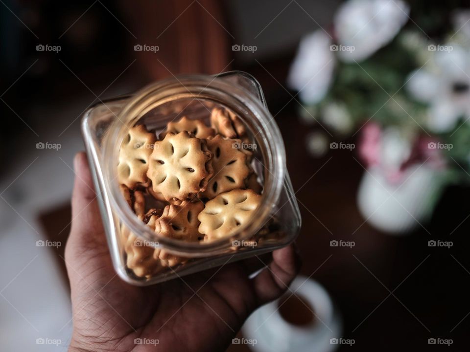 Me holding a mini pineapple jam cookies in a glass jar