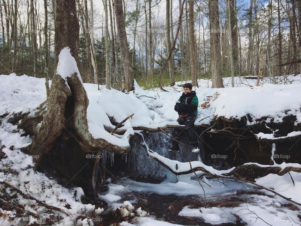 Exploring a frozen waterfall in a forest stream