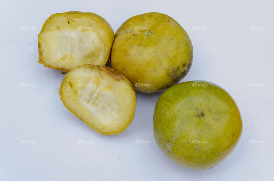 Ripe White Sapote cut and whole on white surface
