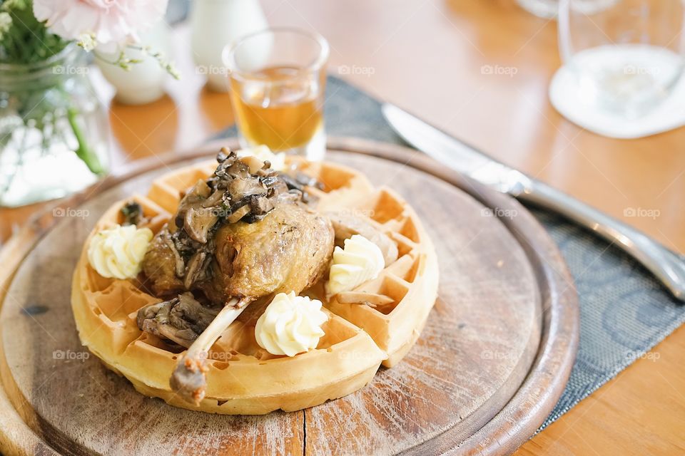 Waffles. Waffle served for brunch with duck and mushroom. Selective focus on crispy duck leg. Duck Confit Waffle with mushroom and butter.