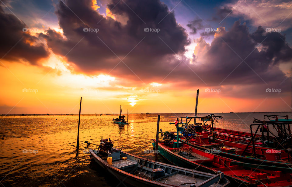are fishing boat on the sea water and sun is background.