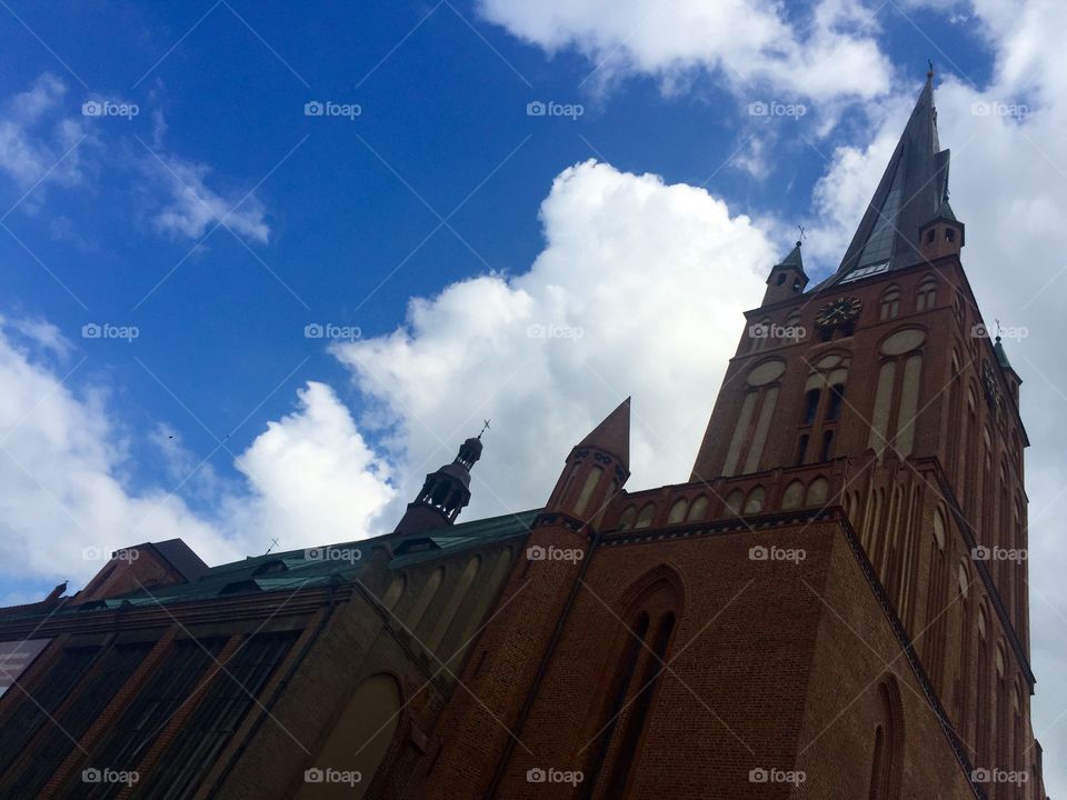 A Roman Catholic Church from the human's point of view against the cloudy sky on a sunny day 