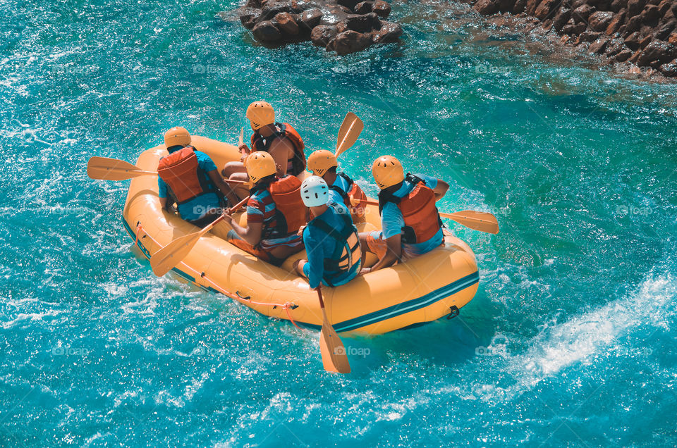 Group of friends enjoy rafting in a fast moving water.