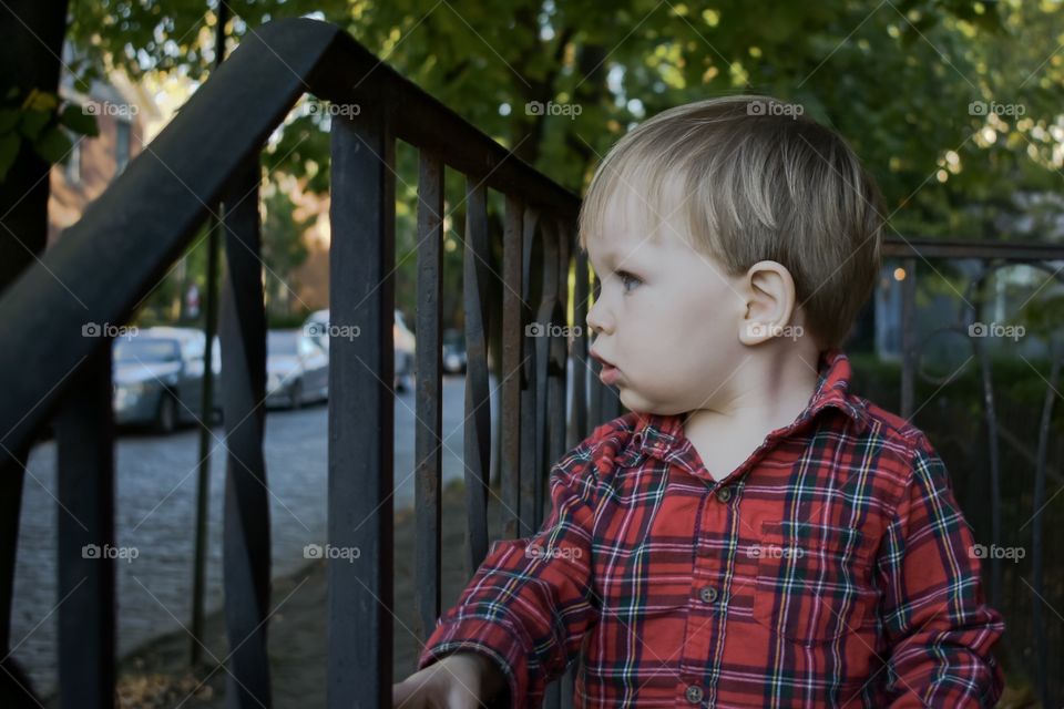 Cute curious toddler watching street from porch 