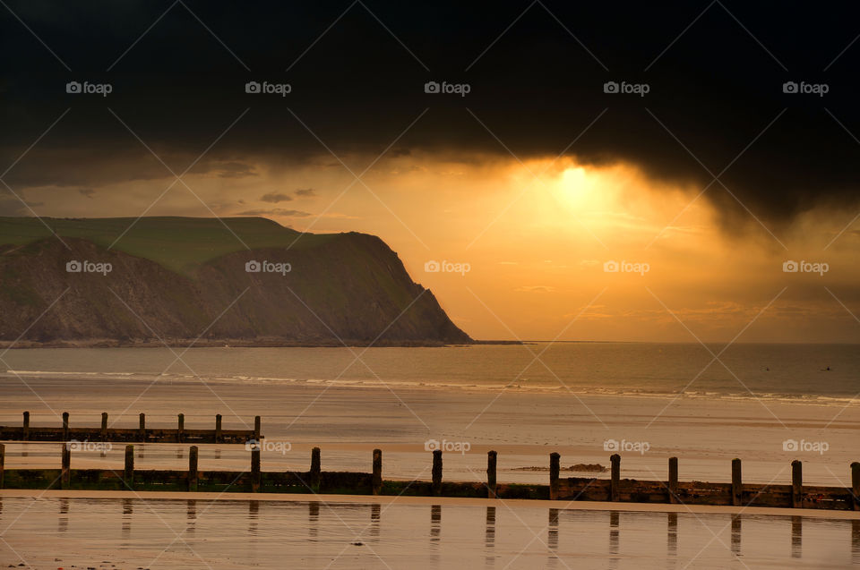 Dramatic sunset over Welsh coastline with cliffs. UK.